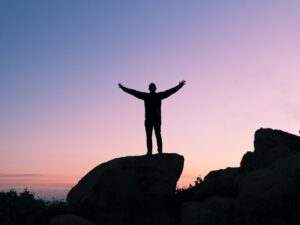 Person standing on a rock with open arms. He is free