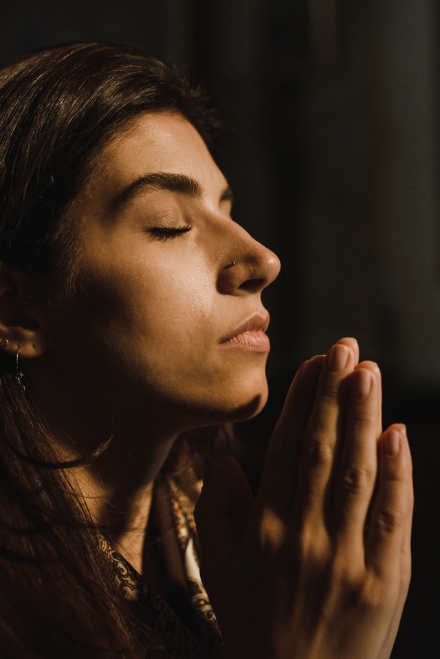 A woman with her hands joined together in prayer.
