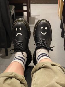 two feet with black shoes. one with happy smile, other with sad smile
